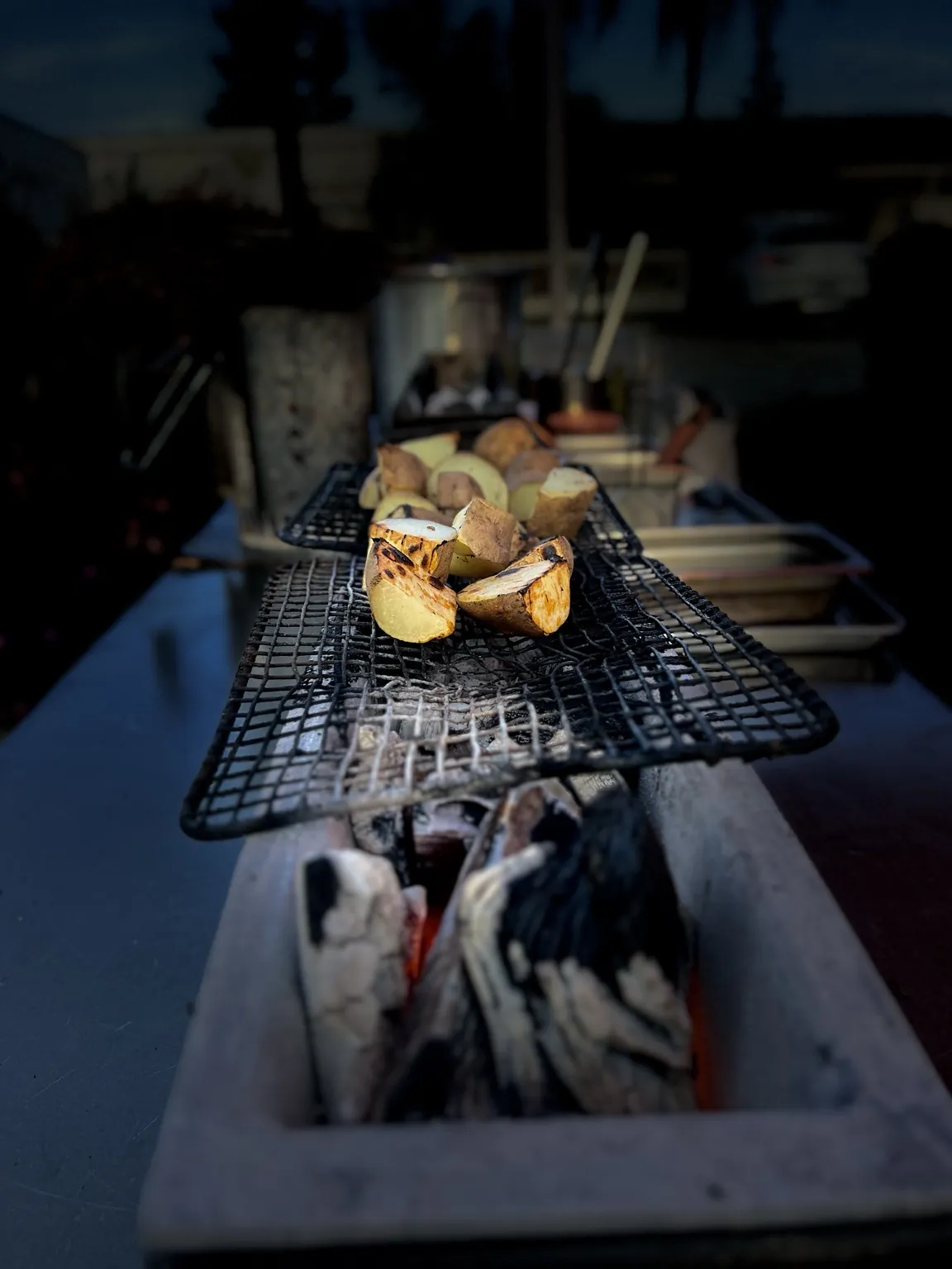 Charred potatoes at dusk on the live-fire grill